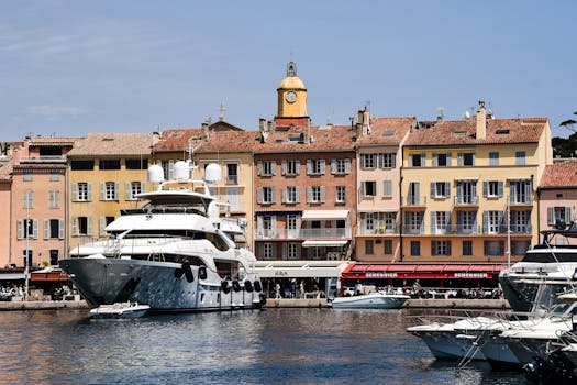 Scenic view of luxury yachts docked at Saint-Tropez harbor with charming French architecture.